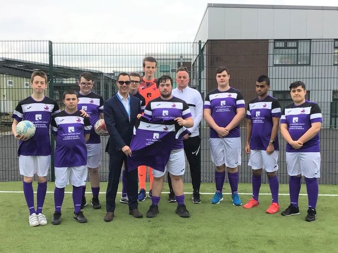 Phil Bird of The PC Support Group presents the Rumworth School football team with their new kit